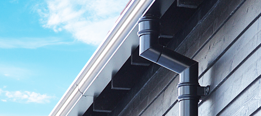 Black aluminium traditional round downpipe and white moulded ogee guttering