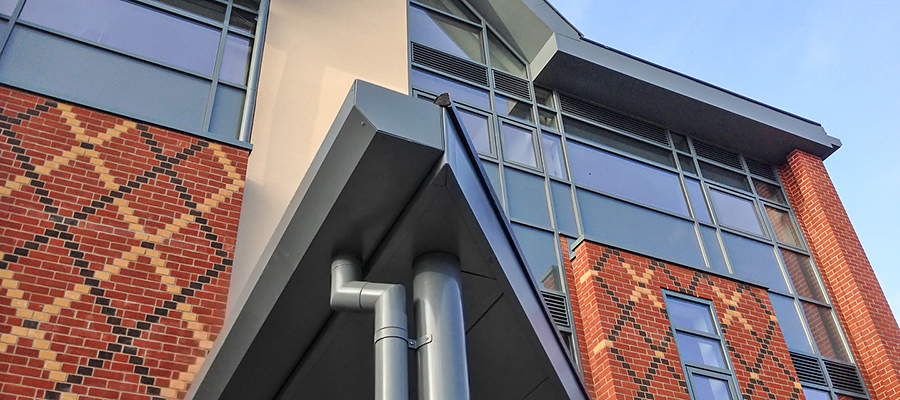 Grey aluminium shaped box gutter fitted to modern build with round downpipes