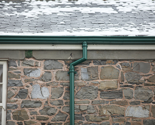 guttercrest aluminium traditional cast round downpipes with moulded ogee gutters in green fixed to air ambulance building in newtown