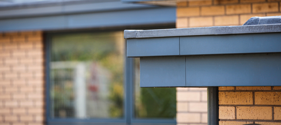 guttercrest aluminium primary trio fascia fitted to modern build with round downpipes in grey