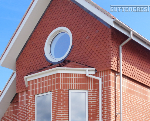 lose-up of Guttercrest grey half-round aluminium guttering system with fascia, soffit, and downpipe in RAL 7035 finish.