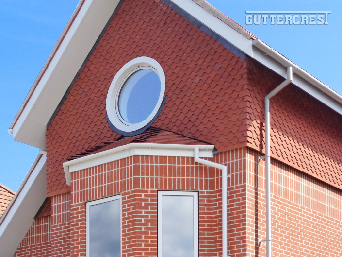 lose-up of Guttercrest grey half-round aluminium guttering system with fascia, soffit, and downpipe in RAL 7035 finish.